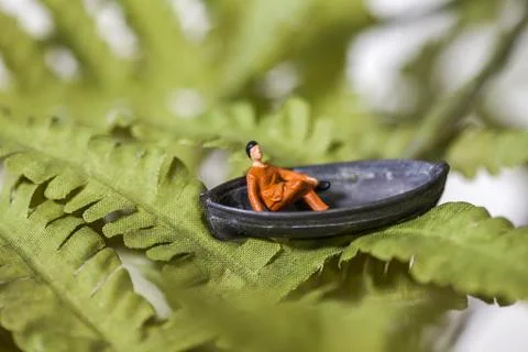 Tiny man sitting in a boat Foto stock