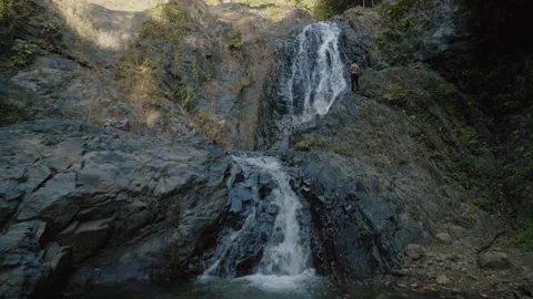 Tiny Man Standing against of Waterfall in Valley Mountain Stock Footage 154017017