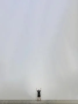 Tiny man standing facing a huge blank white wall Stock Photos