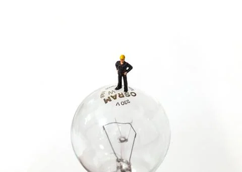 Tiny man standing on a light bulb Stock Photos