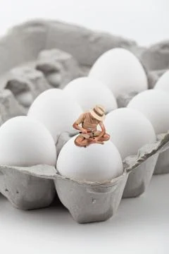 Tiny man trying to break an egg Stock Photos