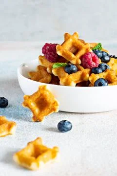 Tiny (Mini) waffles for breakfast with berries in a white bowl Foto stock