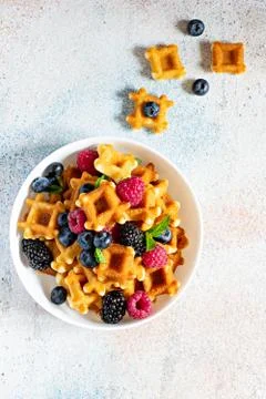 Tiny (Mini) waffles waffles with berries in a white bowl on a light background. Stock Photos