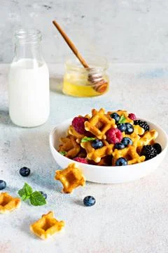 Tiny (Mini) waffles waffles with milk for breakfast with berries in a white bowl Foto stock