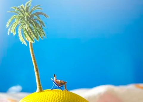 Tiny miniature man sitting at beach chair looking at sea Stock Photos