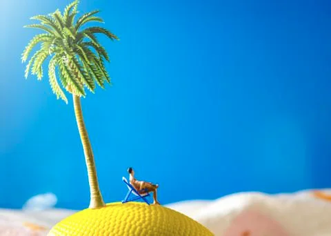 Tiny miniature man sitting at beach chair looking at sea Stock Photos