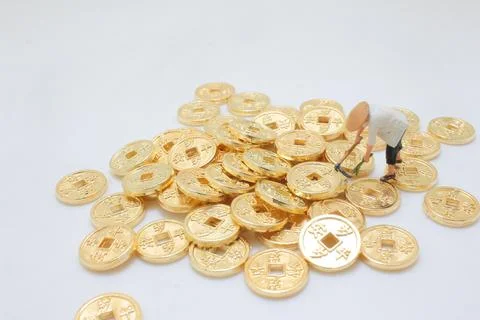 Tiny model laborer clears scattered coins in playful scene Stock Photos