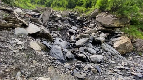 Tiny mountain stream flowing calmly on rough rocks, boulders and pebbles, Video stock 292119861