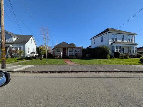 Tiny narrow home squeezed between larger houses, with green lawn Stock Photos