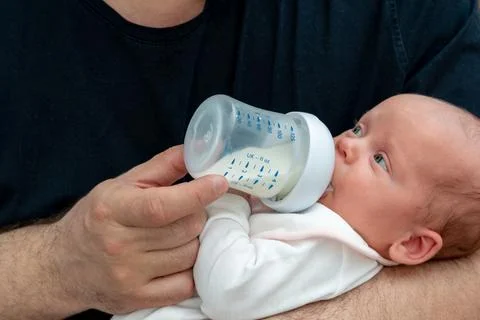 Tiny newborn baby eats milk formula from a bottle Foto stock