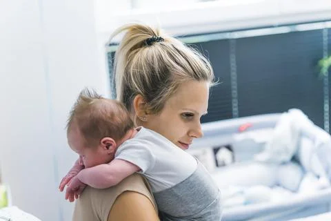 Tiny newborn boy laying on his happy loving mother shoulder and looking behind Stock Photos
