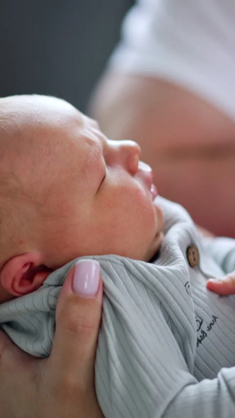 Tiny newborn child in blue romper in mom's hands.  Stock Footage 301880497