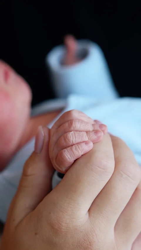 Tiny newborn child wearing blue romper in the parent's hands. Stock Footage 304506234