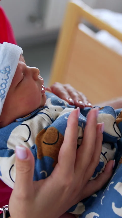 Tiny newborn in romper and cap lies between his parents on their hands.  Stock Footage 301880557