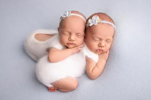 Tiny newborn twin girls. A newborn twin embraces and sleeps on his sister. Stock Photos
