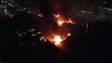 Tiny people seen putting object in raging fire viewed by drone flying over riot 库存影片 134505947