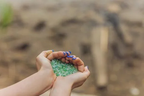 Tiny pieces of plastic collected from sandy beach in hands of environmentalist 库存照片