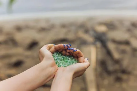 Tiny pieces of plastic collected from sandy beach in hands of environmentalist Foto stock