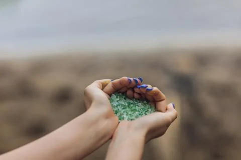 Tiny pieces of plastic collected from sandy beach in hands of environmentalist Foto stock