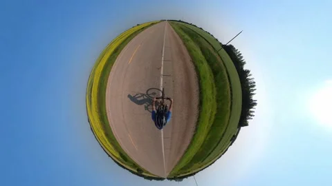 Tiny planet 360 degree action camera view looking down on a man pedalling a bike Stock Footage 280320946