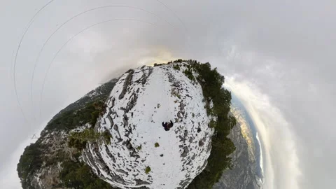 Tiny planet effect capturing a man walking through a snowy mountain ridge Stock Footage 298451698