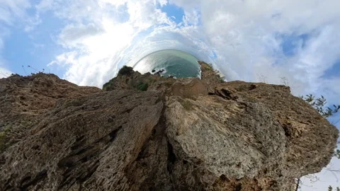 "Tiny planet" effect showcasing dramatic cliffside rocks curving toward the Stock Footage 293718619