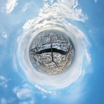 Tiny planet in sky with clouds overlooking winter old town, urban development Stock Photos