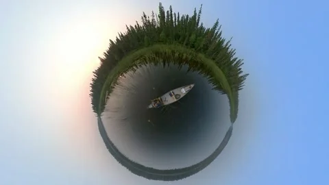 Tiny planet view of a person with a fishing rod paddling a canoe through reeds  Stock Footage 247741516
