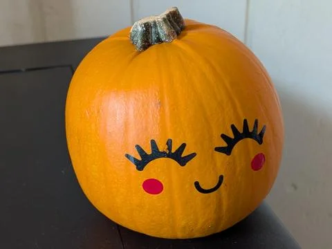 A tiny pumpkin painted with a joyful face, red cheeks, and eyebrows 写真素材