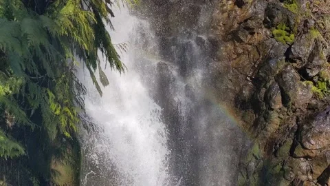 A tiny rainbow forms in the cool mist of a clean magical waterfall in a Stock Footage 194502713