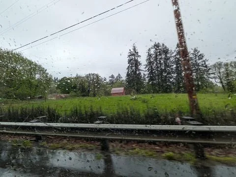 Tiny red barn surrounded by lush green pasture and trees Stock-Fotos