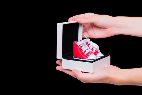 Tiny Red Canvas Shoes in a Small Gift Box in Hands Stock-Fotos