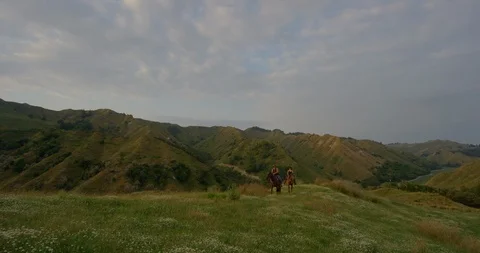 Tiny riders on horseback on distant green hilltop under moody sky Stock-Footage 102926096
