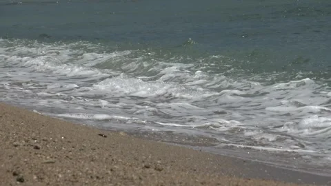 Tiny sea waves softly reaching the beach shore during a bright summer Stock Footage 330589286