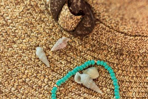 Tiny seashells and bracelet on woven hat. Stock Photos