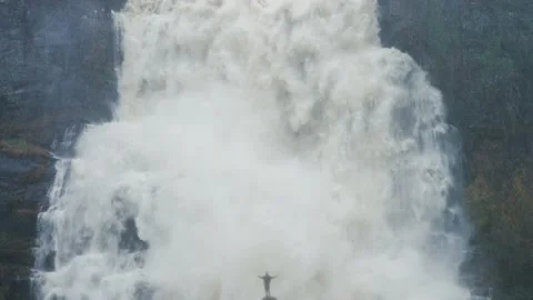 A tiny silhouette of a person in front of the huge raging Tvinderfossen Stock Footage 195717056