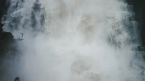 A tiny silhouette of a person under the huge raging Tvinderfossen Stock Footage 195717241