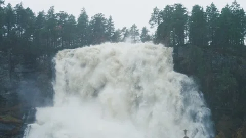 A tiny silhouette of a person under the huge raging Tvinderfossen Stock Footage 195717376