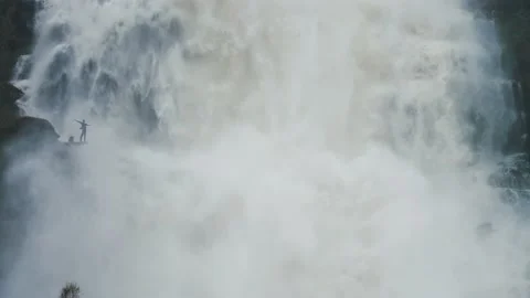 A tiny silhouette of a person under the overflowing raging Tvinderfossen Video stock 195717160