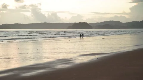 Tiny silhouette romantic couple on beach, cloudy sky on evening Stock Footage 153507446