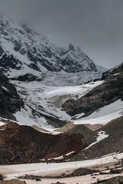 Tiny silhouettes of people against the backdrop of the Chalaadi glacier in .. Stock Photos