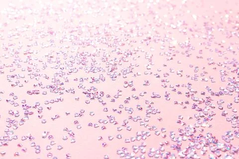 Tiny silver crystal confetti on a pink background. Stock Photos