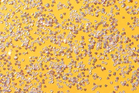 Tiny silver crystal confetti on a yellow background. Stock Photos