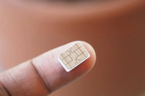 Tiny SIM card held on a finger in close-up view Foto stock