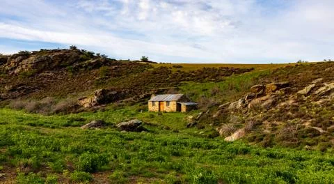 A TIny Stone Cabin Sits On This Cold Hill In Otago Stock Photos