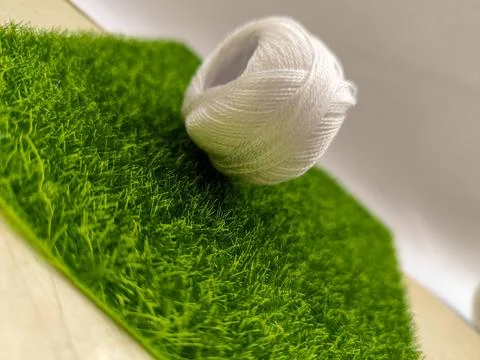A tiny thread spool sits on lush green. Soft focus and warm light enhance t.. Stock Photos