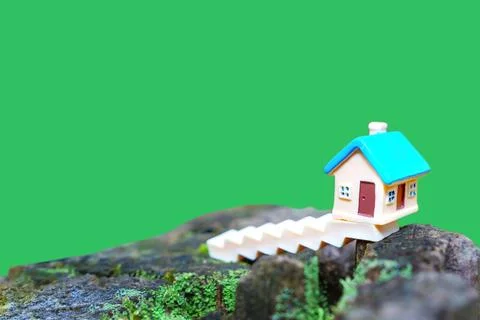 Tiny Toy House Set on a Tree Stump against Clean Green Backdrop Foto stock