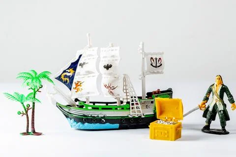 A tiny toy pirate ship with a treasure chest and a statue of a pirate on wh.. Stock Photos