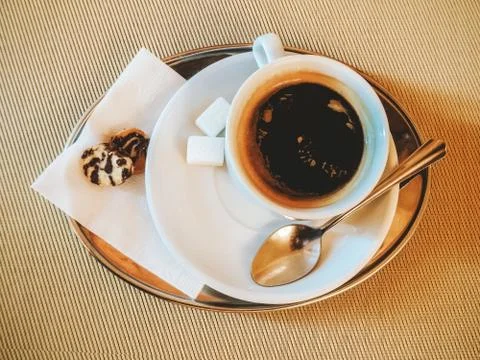 A tiny tray with a cup of black coffee, sugar cubes and small cookies. Photo in Stock Photos
