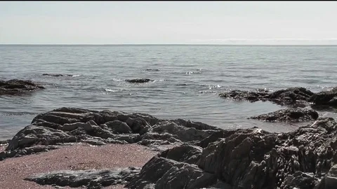 Tiny waves hitting the rock on a cloudy day with sunny period. Video stock 81786812